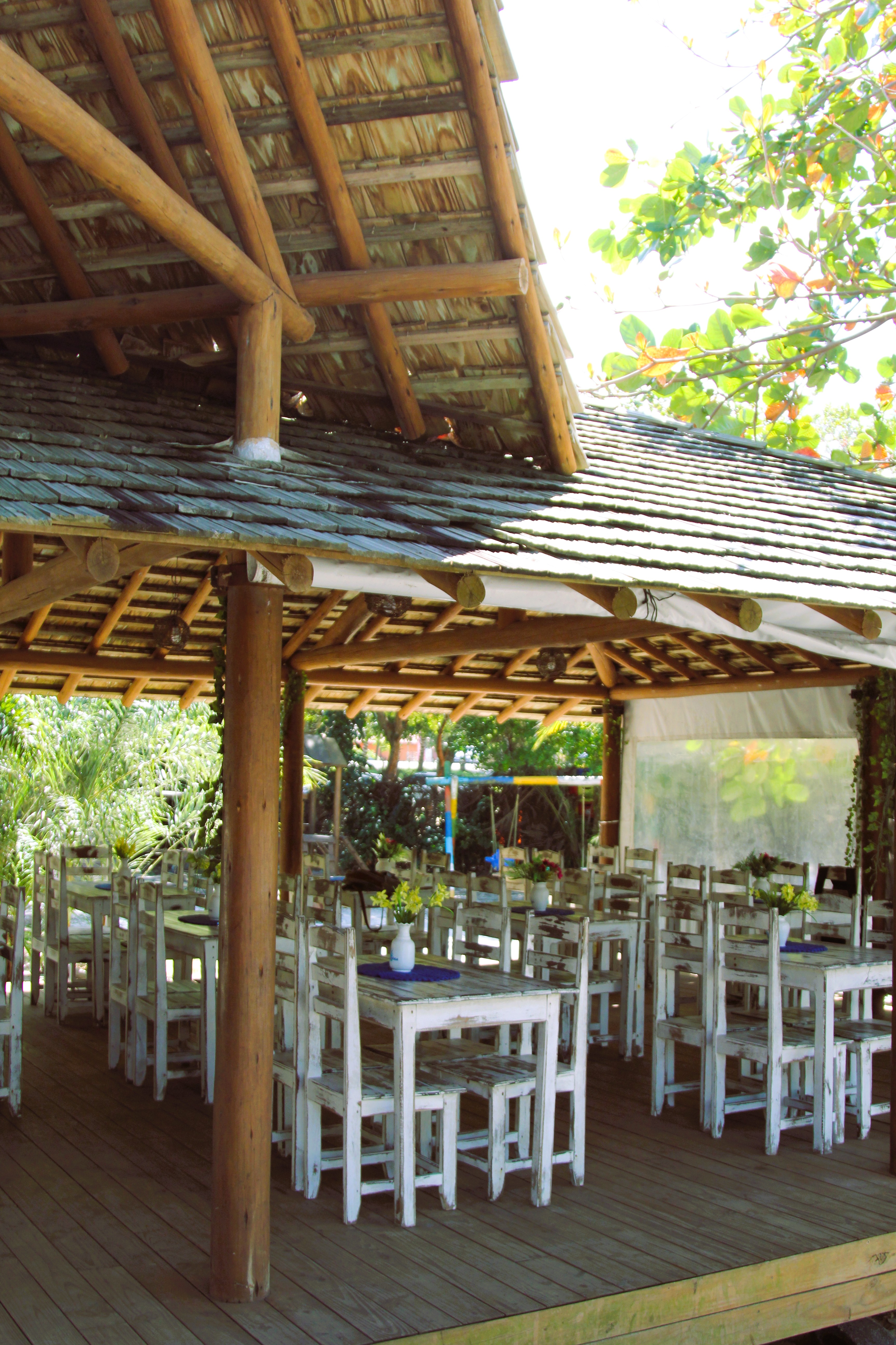 Salão interno com mesas de madeira e telhado de palha